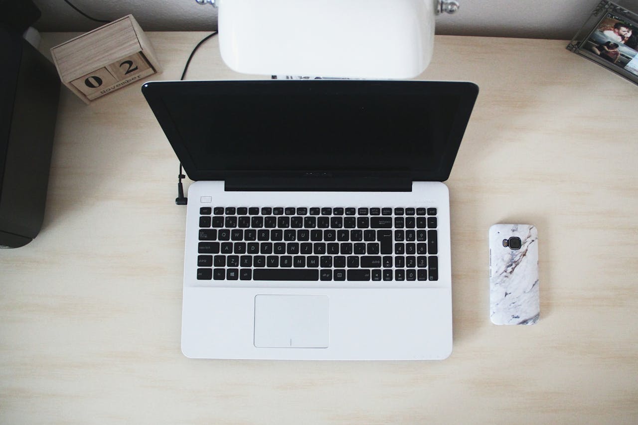 Top view of a minimalist workspace featuring a laptop, smartphone, and desk accessories.